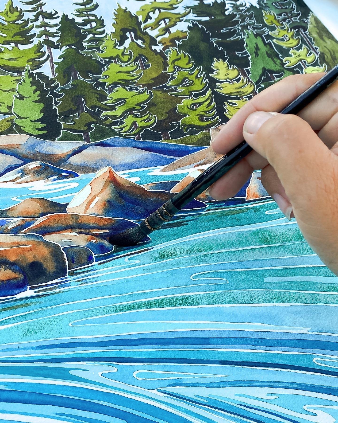 Hand holding a watercolour brush painting a vivid turquoise seascape